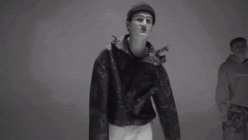 a black and white photo of a young man wearing a beanie and jacket .