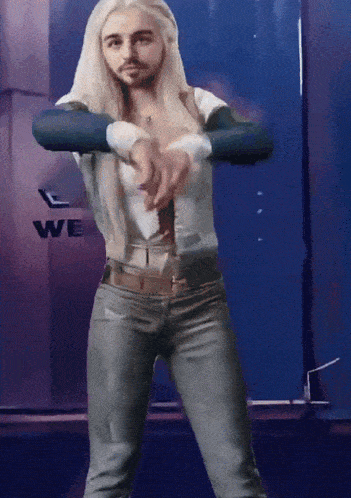 a man with blonde hair is dancing in front of a wall with the word we on it