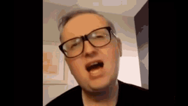 a man wearing glasses is making a funny face and talking .