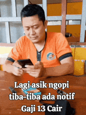 a man sitting at a table looking at his phone with the caption lagi asik ngopi tiba-tiba ada notif gaji 13 cair
