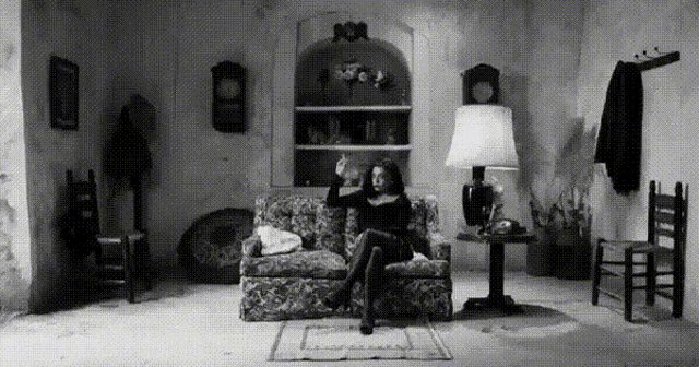 a woman sits on a couch in a living room with a lamp