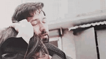 a man is holding a woman 's head in his arms while they are hugging .