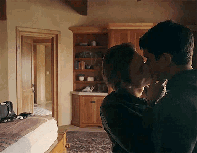 a man and woman are kissing in a bedroom