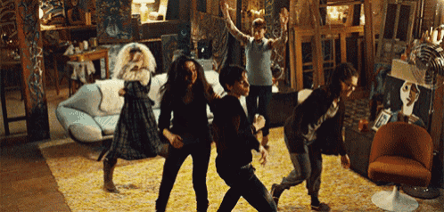 a group of people are dancing in a living room in front of a couch and chair .