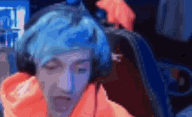 a man with blue hair is wearing headphones and an orange hoodie