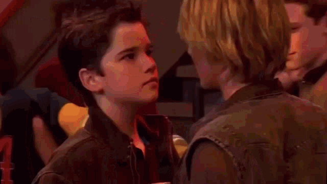 two boys are standing next to each other in front of lockers in a school .