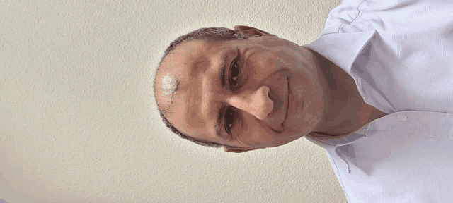 a man wearing a white shirt is smiling and looking down