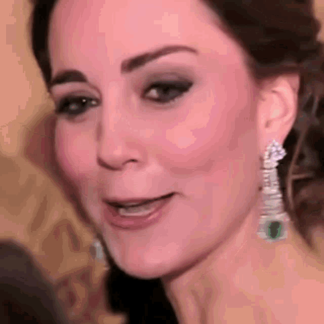 a close up of a woman 's face wearing emerald earrings .