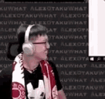 a man wearing headphones and a scarf is standing in front of a computer .