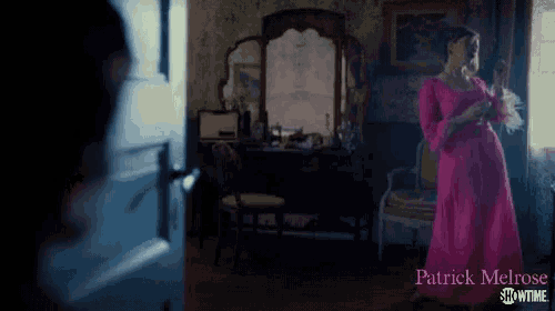 a woman in a pink dress is standing in a dark room with patrick melrose showtime written in the corner