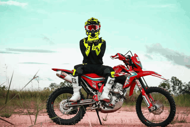 a person sitting on a red dirt bike with the letter g on the side