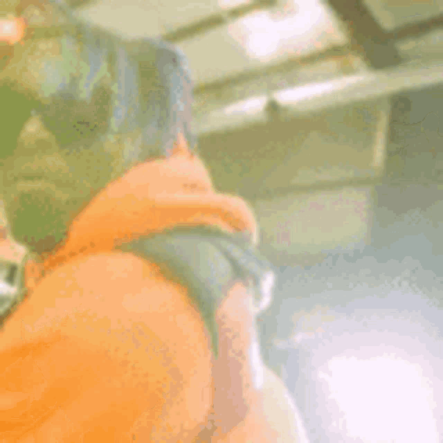 a man with purple dreadlocks and sunglasses is wearing an orange hoodie .