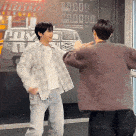 two men are dancing in front of a sign that says ' nyc '