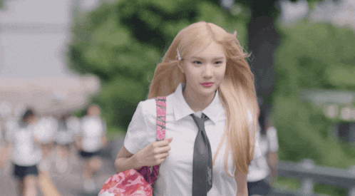 a girl with blonde hair wearing a white shirt and tie carrying a pink bag that says i love you