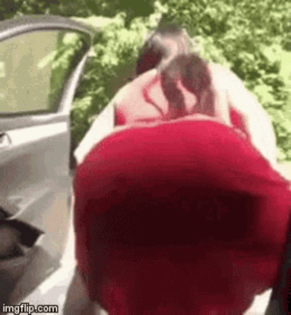 a woman in a red dress is getting out of a car with her back to the camera .