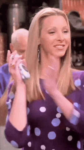 a woman in a purple polka dot shirt is holding a cell phone and smiling