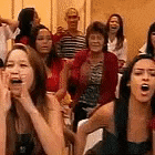 a group of people are sitting in a room applauding and laughing .