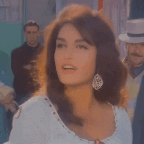 a woman in a white dress and earrings is looking at the camera .