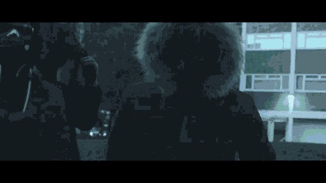 a man in a black jacket with a fur hood is standing next to another man