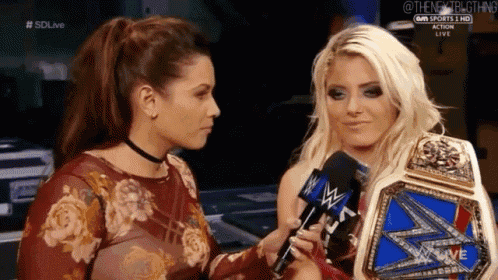 two women are standing next to each other and talking into microphones .