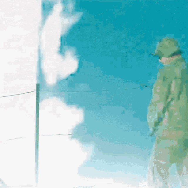 a man in a green uniform stands in front of a blue sky with clouds