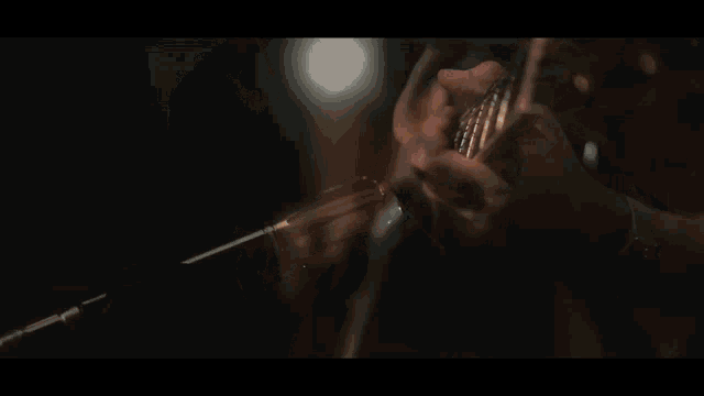 a man is playing an acoustic guitar in the dark