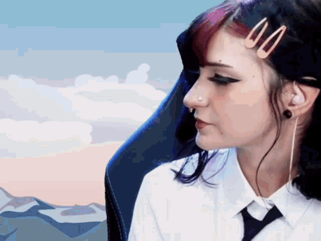 a woman with a nose ring and earrings is wearing a white shirt and tie