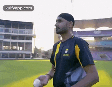 a man is holding a cricket ball on a field .