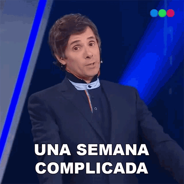 a man in a suit says una semana complicada on a blue background