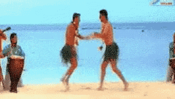 a couple of men are dancing on a beach