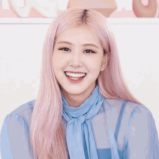 a woman with pink hair wearing a blue shirt and tie smiles