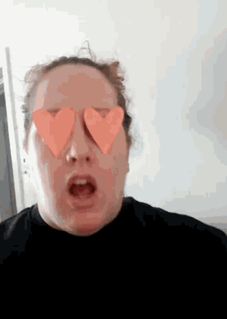 a woman wearing heart shaped glasses is making a face