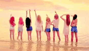 a group of girls are standing in the water on the beach