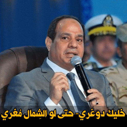 a man in a suit and tie speaking into a microphone with arabic writing below him