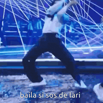 a man is jumping in the air on a stage with the words `` baila si sos de lari '' .