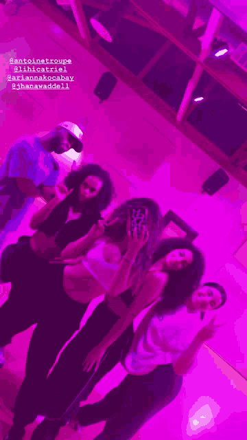 a group of people are posing for a picture in front of a mirror with purple lights behind them
