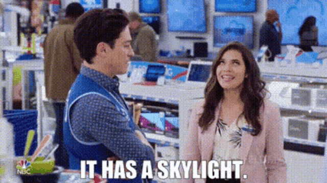 a man and a woman are standing next to each other in a store and talking .
