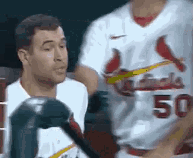 a man in a cardinals jersey is talking to another man in a white jersey .