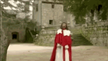 a man in a red robe is standing in front of a castle .