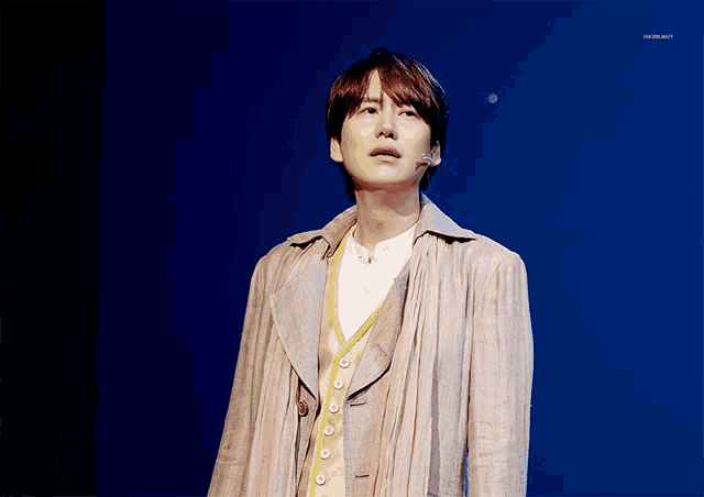 a man stands on a stage in front of a blue background that says ' hazelnut ' on the bottom