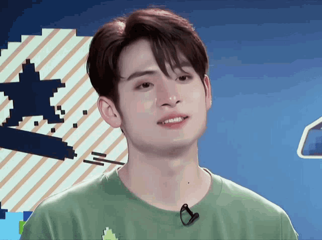 a young man wearing a green shirt with a microphone in front of him