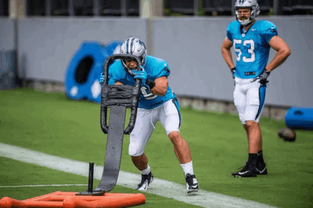 a football player with the number 53 on his jersey is being pushed by a sled