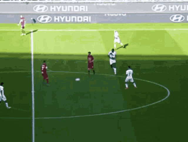 a group of soccer players on a field with hyundai advertisements on the sidelines