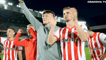 a group of soccer players wearing red and white striped jerseys with the word comarch on them