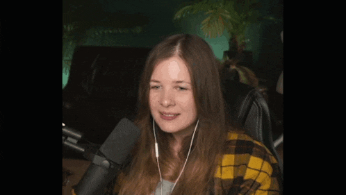 a woman wearing headphones is sitting in front of a microphone and smiling