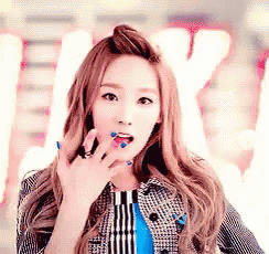 a woman with blue nails is making a surprised face while wearing a plaid jacket and a blue shirt .