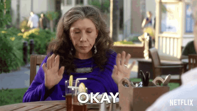 a woman sitting at a table with the word okay written on the screen