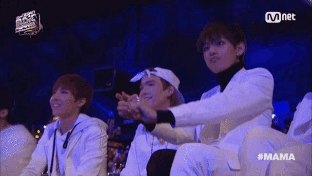 a group of young men are sitting in front of a sign that says mnet