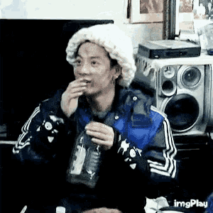 a man is sitting at a table holding a bottle of water and eating a sandwich .