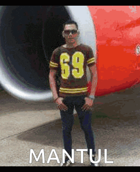 a man wearing a number 69 shirt is standing in front of a red airplane
